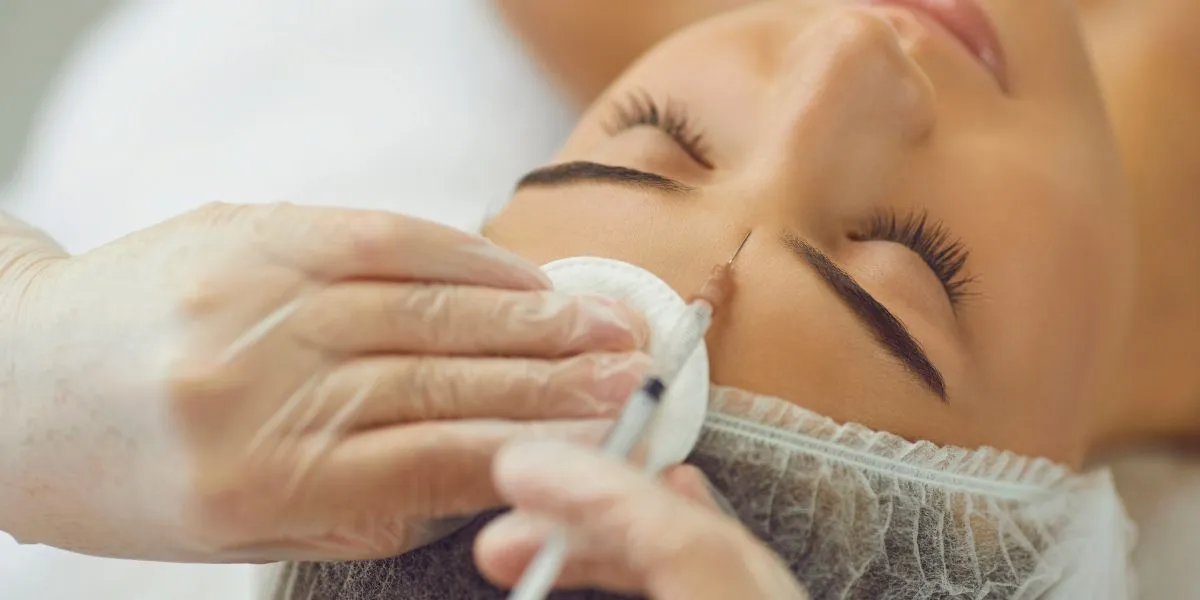 Profesional aplicando un tratamiento antiarrugas con una inyección facial en una clínica estética.